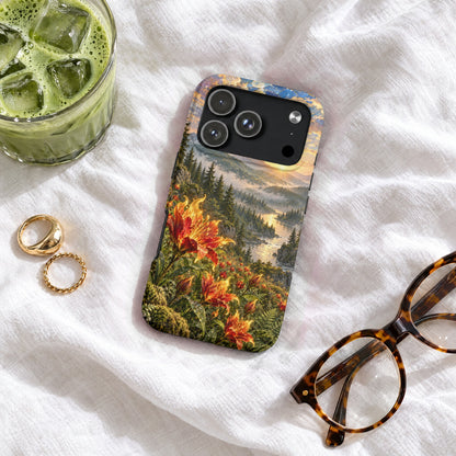 A smartphone case featuring a landscape print of a river valley with orange lilies on a white fabric surface with a glass of iced green tea, two gold rings, and tortoiseshell glasses.