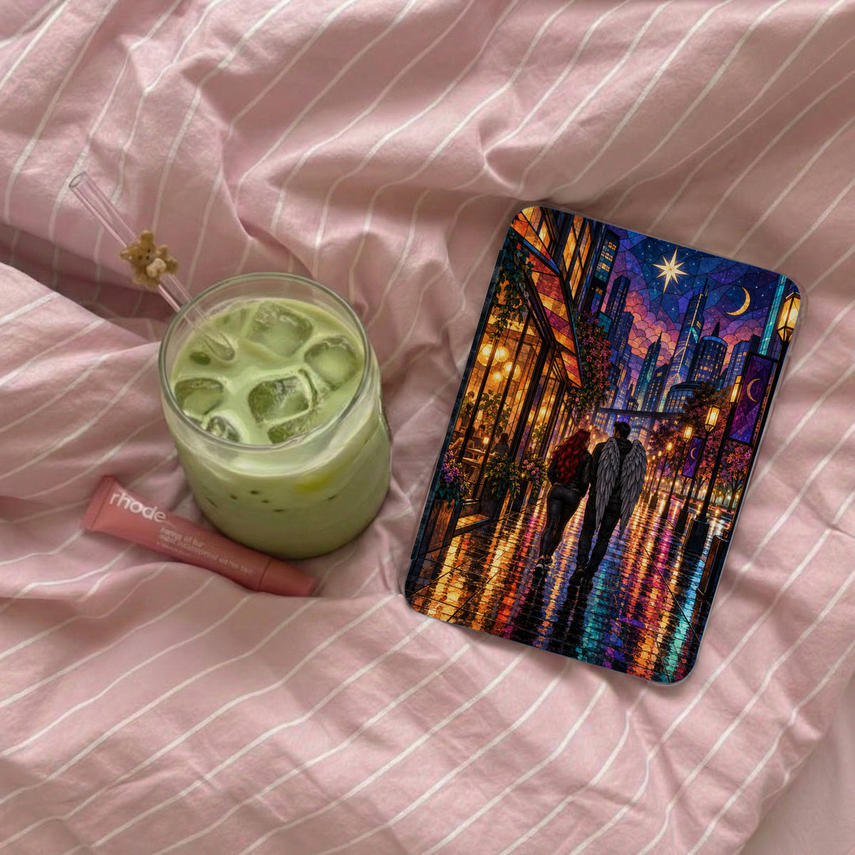 IPhone case with angel wings couple and city at night; iced matcha latte; Rhode lip balm.