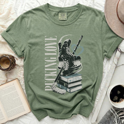 Green t-shirt with hockey skates, stick, books, and text "PUCKING LOVE".