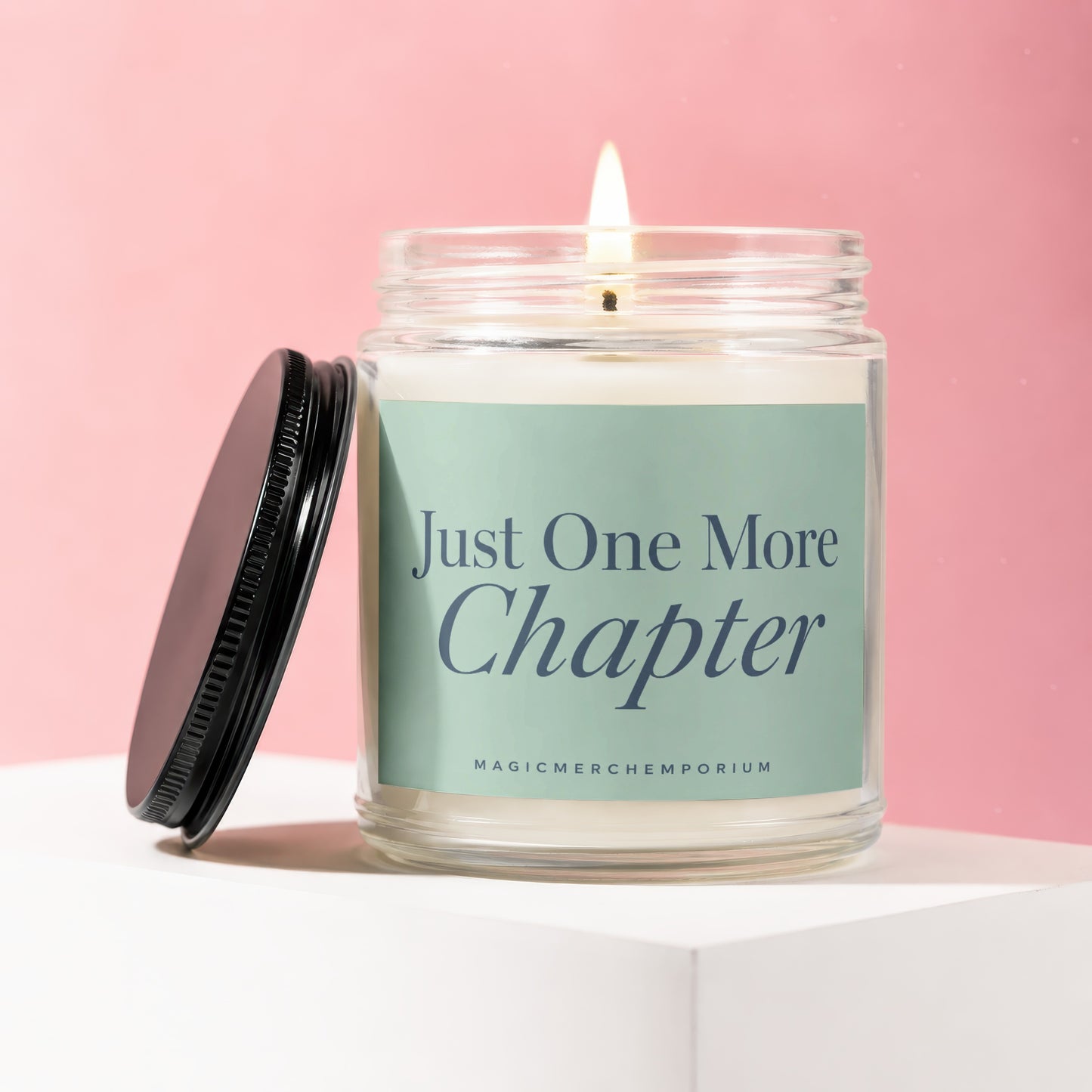 Candle in glass jar with "Just One More Chapter" text on label.