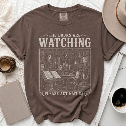 Brown t-shirt with "The Books Are Watching" and a haunted library graphic.