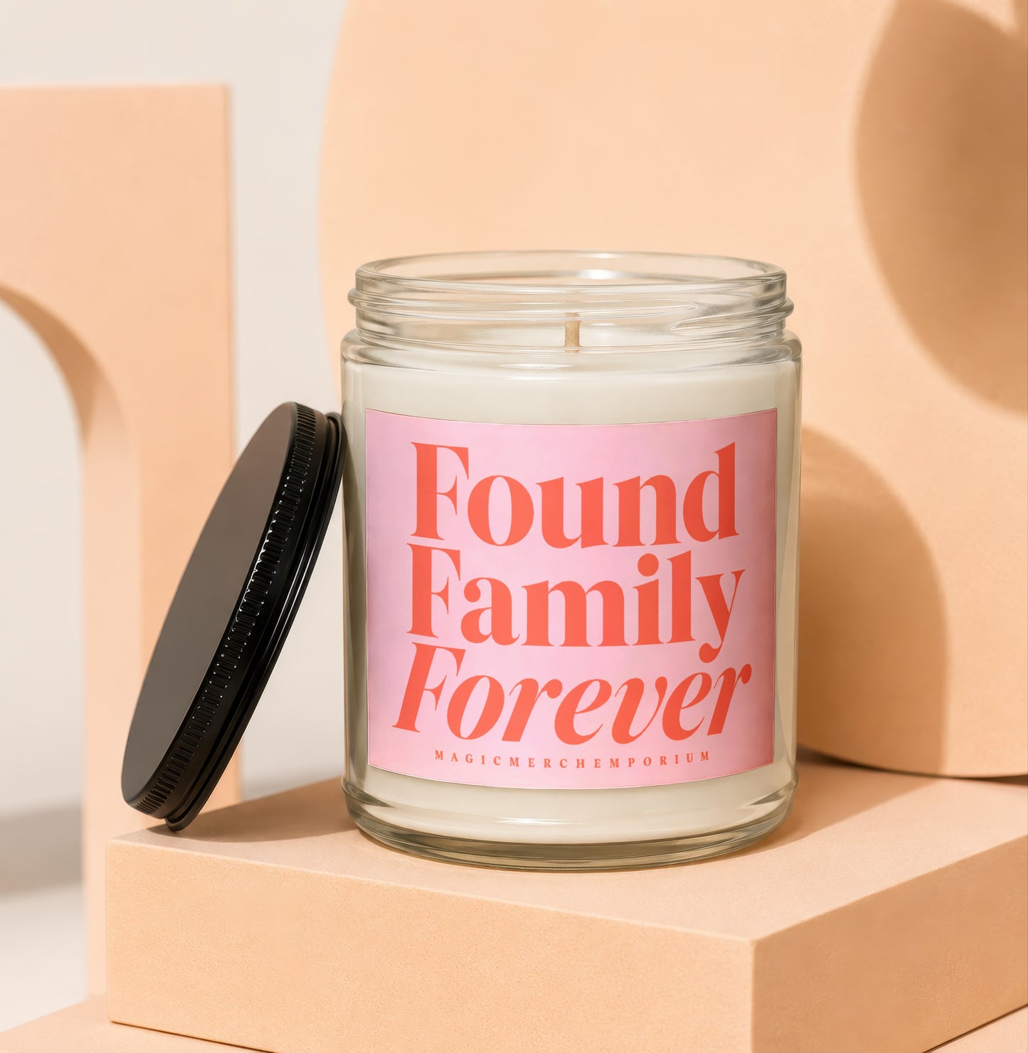 Glass jar candle with pink label reading "Found Family Forever" and "MagicMerchEmporium".