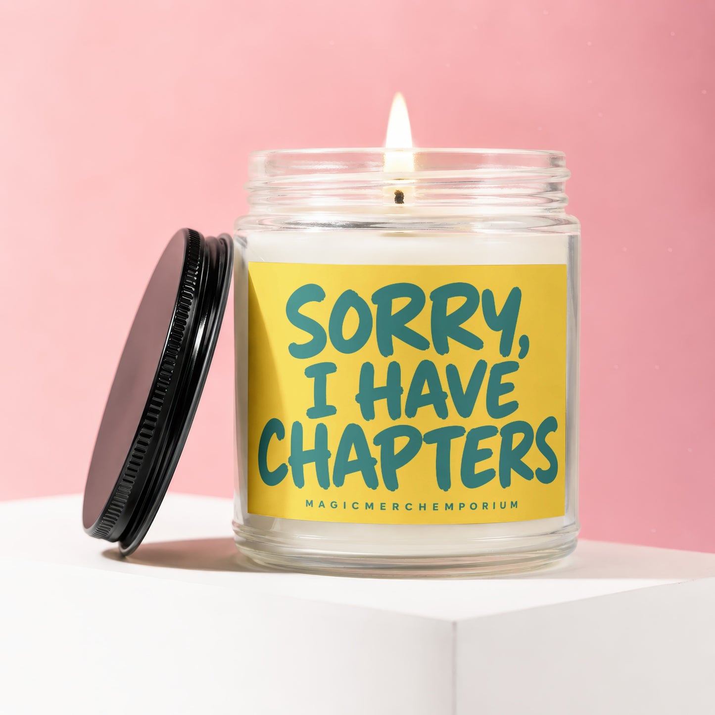 Glass candle with lit wick and black lid, featuring a yellow label with blue text.