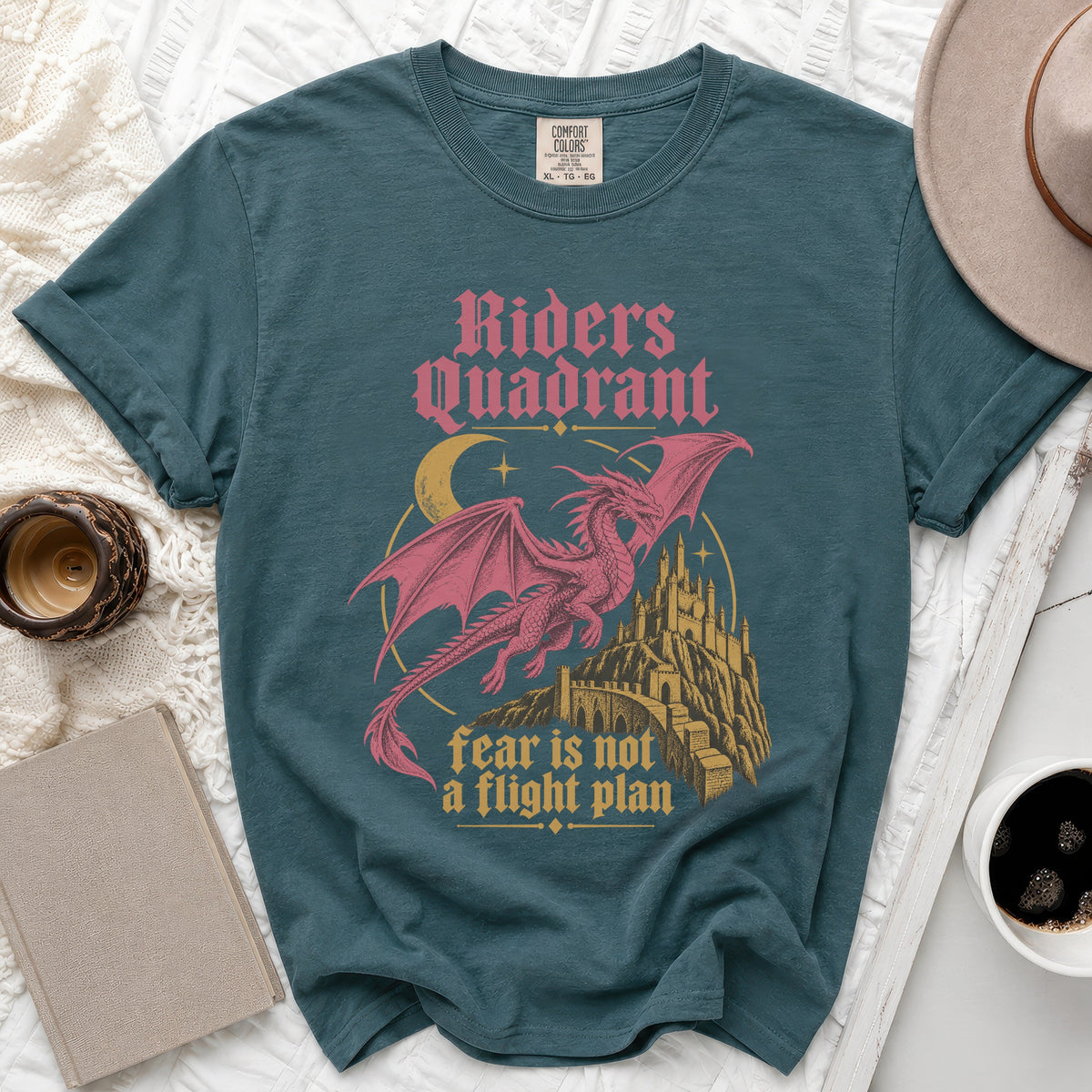 Teal t-shirt with pink dragon, castle, moon, and text: "Riders Quadrant fear is not a flight plan."