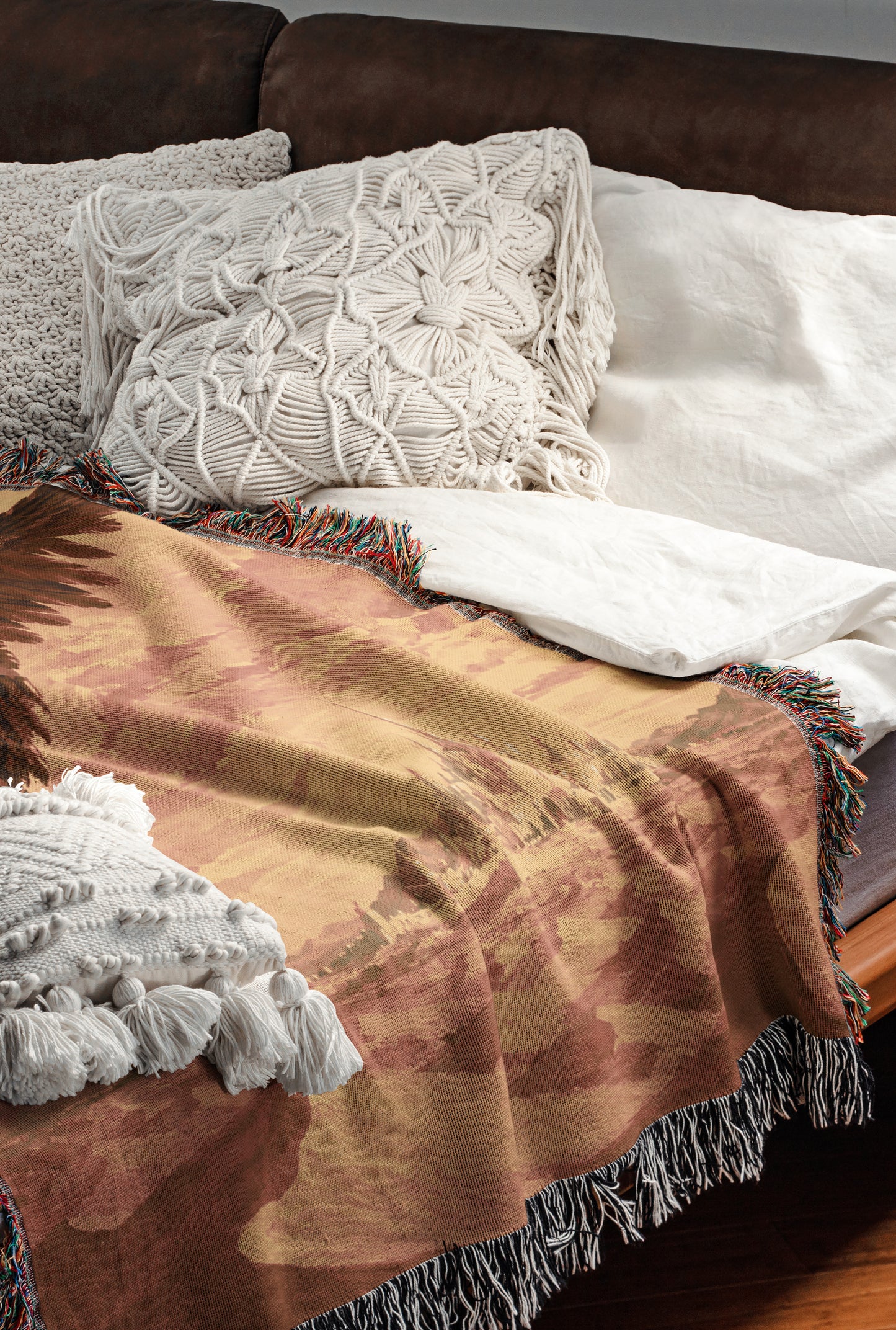 a cozy and inviting bedroom scene, featuring a comfortable bed with a brown blanket and white pillows, as well as a brown leather couch.