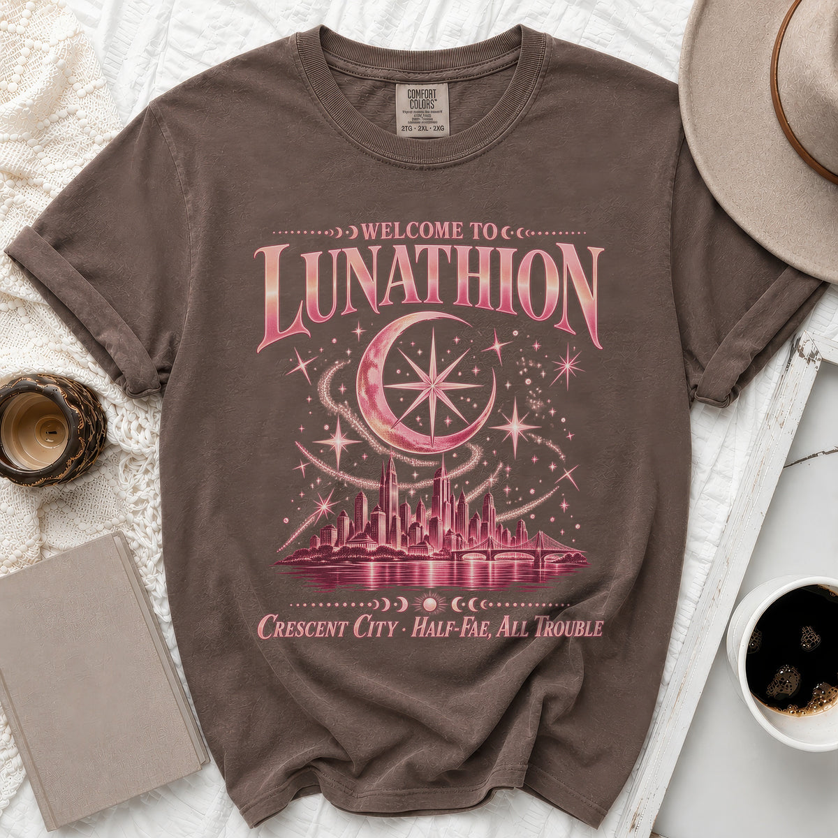 Brown t-shirt with "Welcome to Lunathion, Crescent City, Half-Fae, All Trouble" graphic.