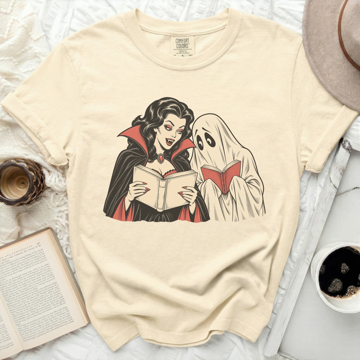 Vampire and ghost reading books together on a cream t-shirt.