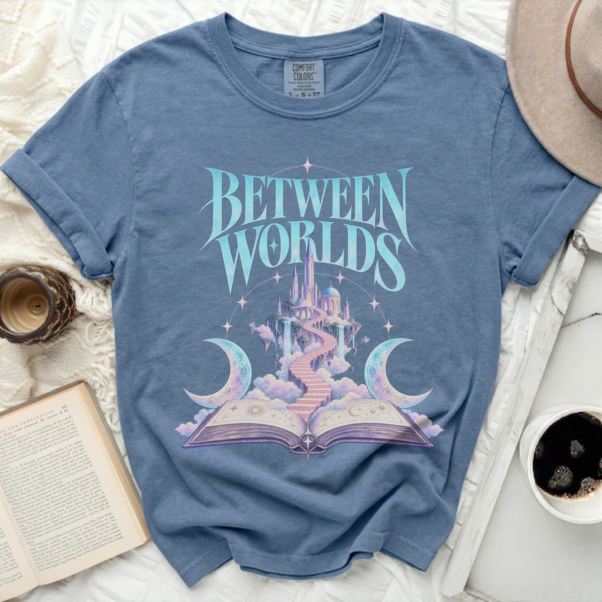 Blue t-shirt with "BETWEEN WORLDS" text and a fantasy castle illustration.