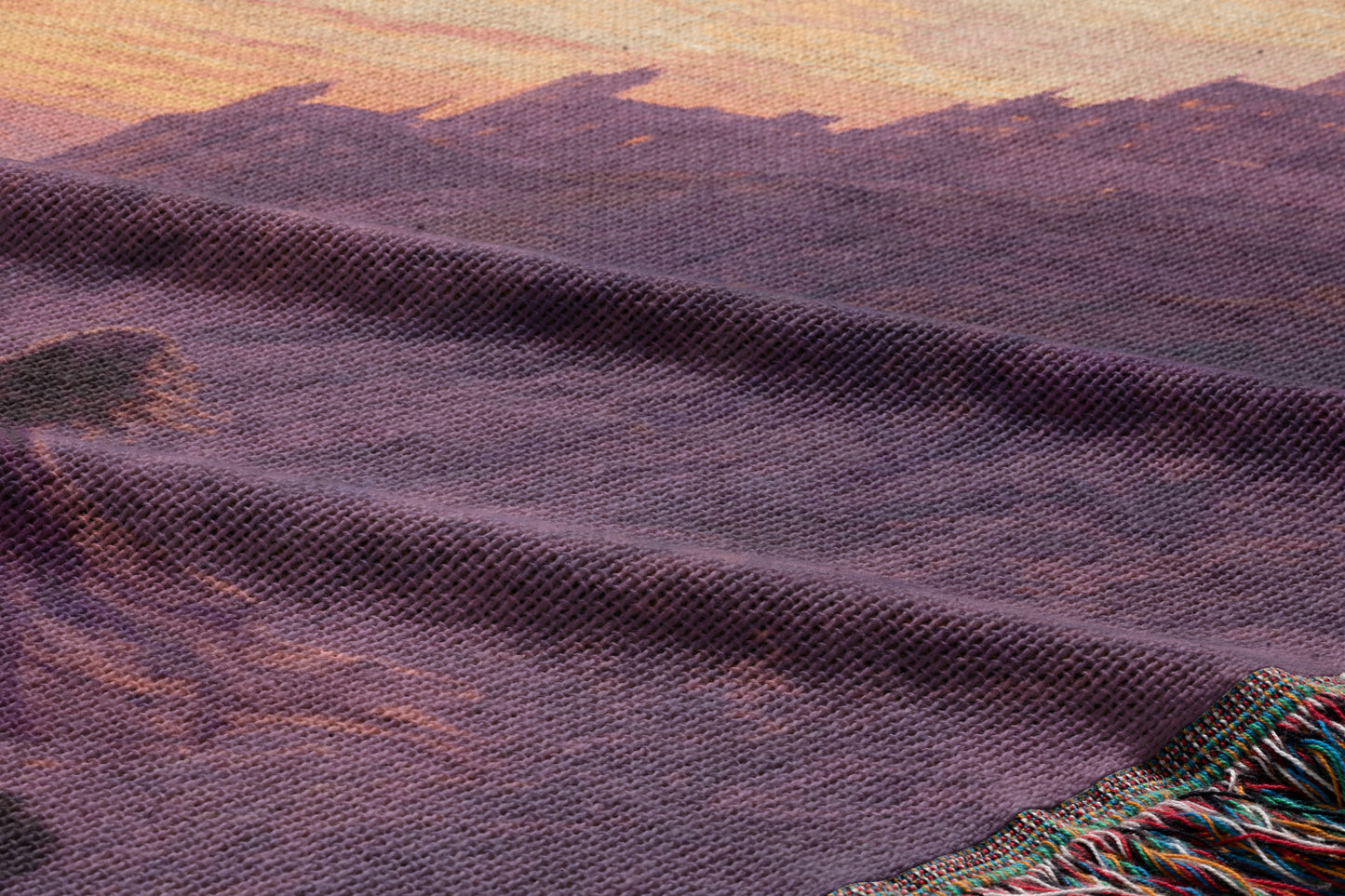 a close-up view of a textured fabric with a mountain landscape printed on it. The fabric appears to be a woven material with a purple hue.