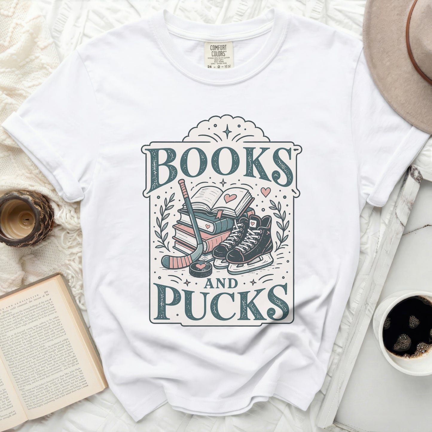 White t-shirt with "BOOKS AND PUCKS" graphic featuring books, hockey skates, and sticks.