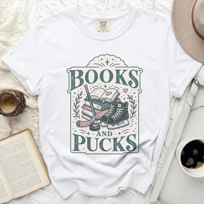 White t-shirt with "BOOKS AND PUCKS" graphic featuring books, hockey skates, and sticks.