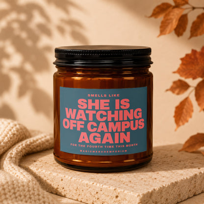 Amber candle with label: "She Is Watching Off Campus Again. For The Fourth Time This Month. MagicMerchEmporium."