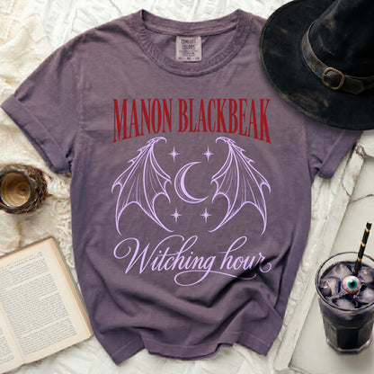 Purple t-shirt with "Manon Blackbeak" and "Witching hour" text and bat wings.