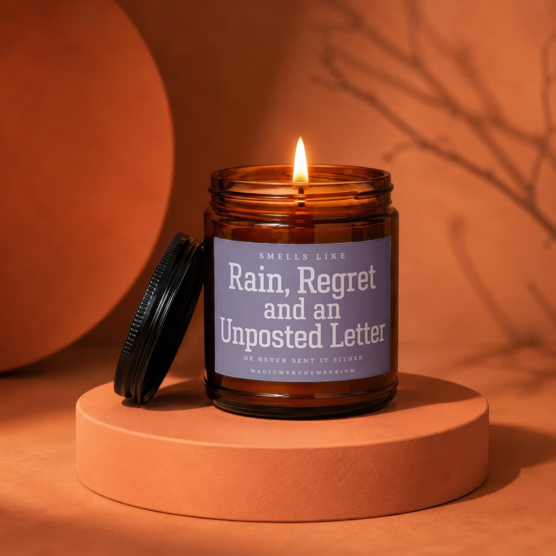 Amber jar candle with lit flame, labeled "Rain, Regret and an Unposted Letter."