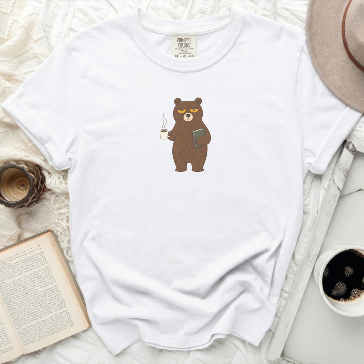 White t-shirt with a grumpy bear holding coffee and a book.