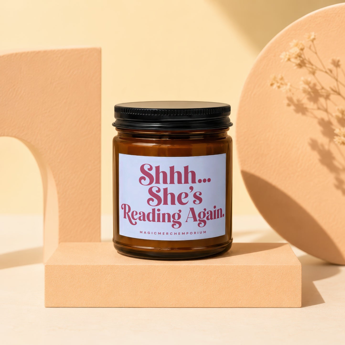 Amber jar candle with white label reading "Shhh... She's Reading Again."