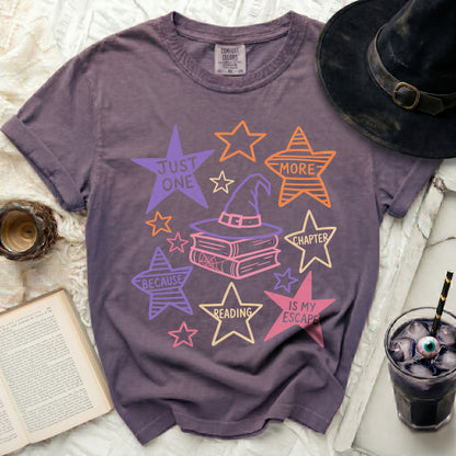 Purple graphic t-shirt with witch hat, books, and stars.