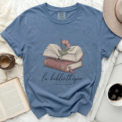 Blue t-shirt with an open book and flower illustration and text.