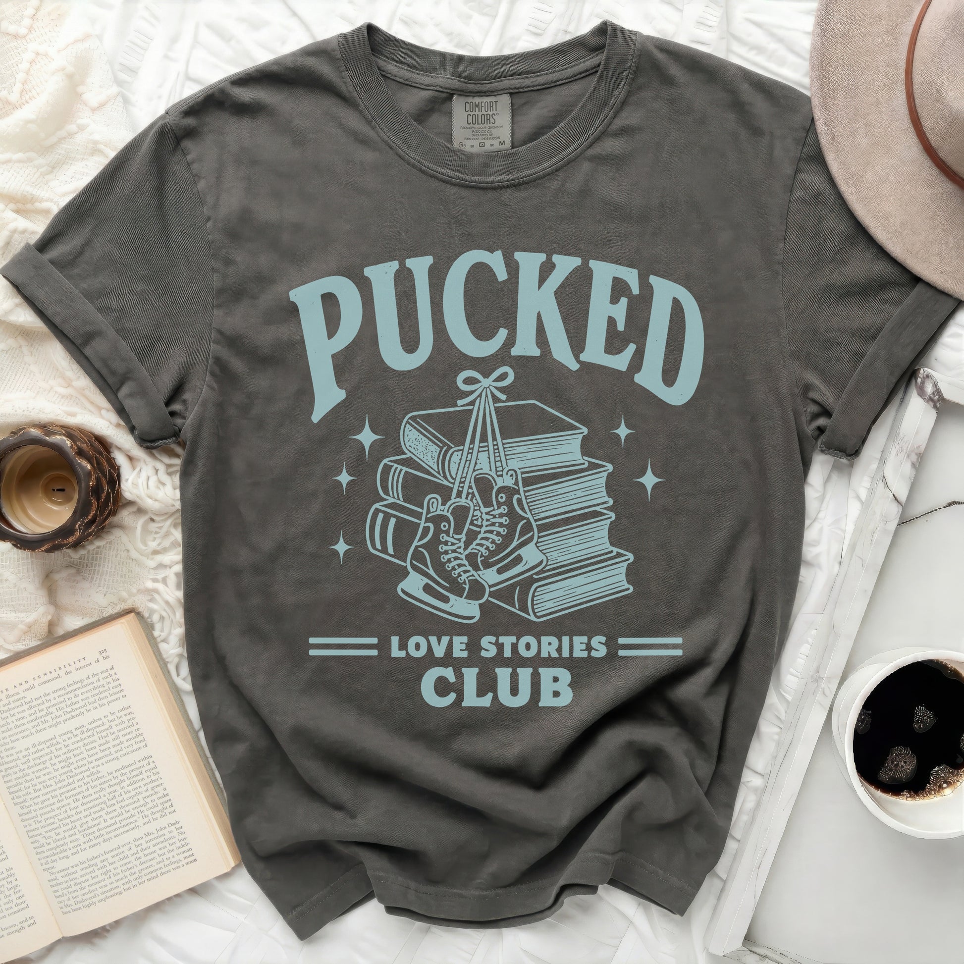 T-shirt with "Pucked Love Stories Club" and ice skates over books.