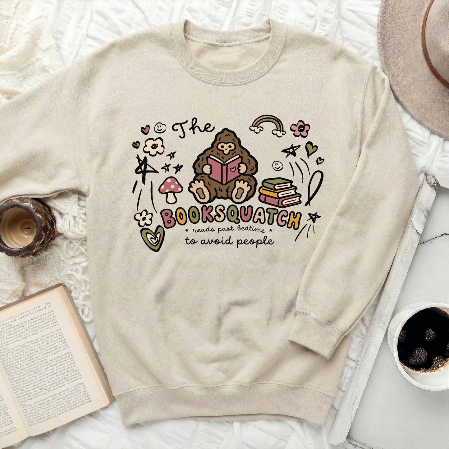 Cream sweatshirt with "The Booksquatch reads past bedtime to avoid people" graphic.