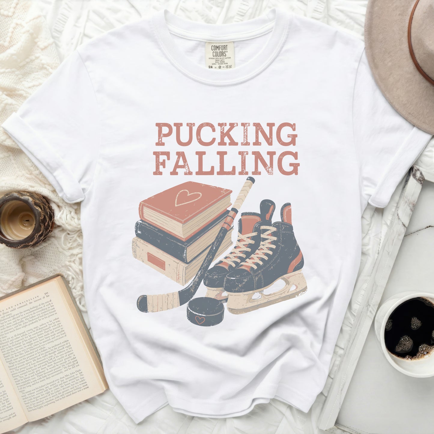 White t-shirt with "PUCKING FALLING" text and hockey gear.