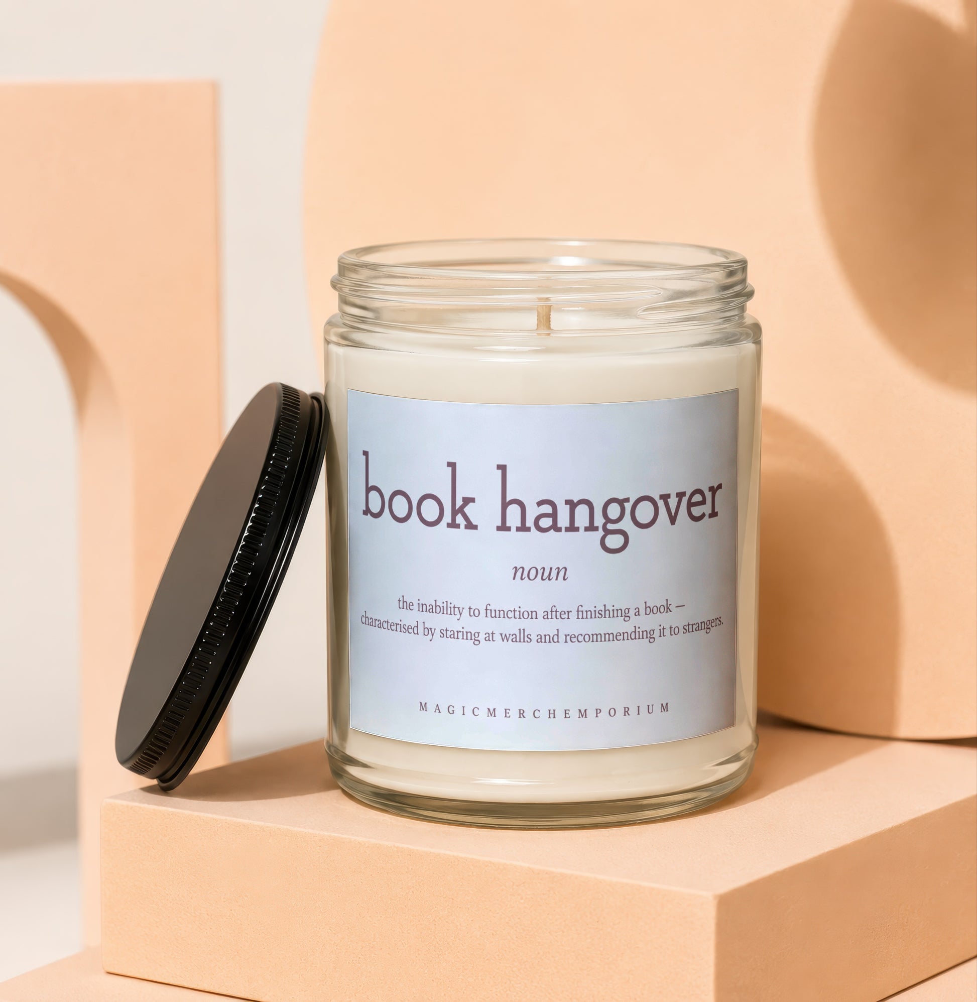 Jar candle with "book hangover" definition and "MAGICMERCHEMPORIUM" logo.