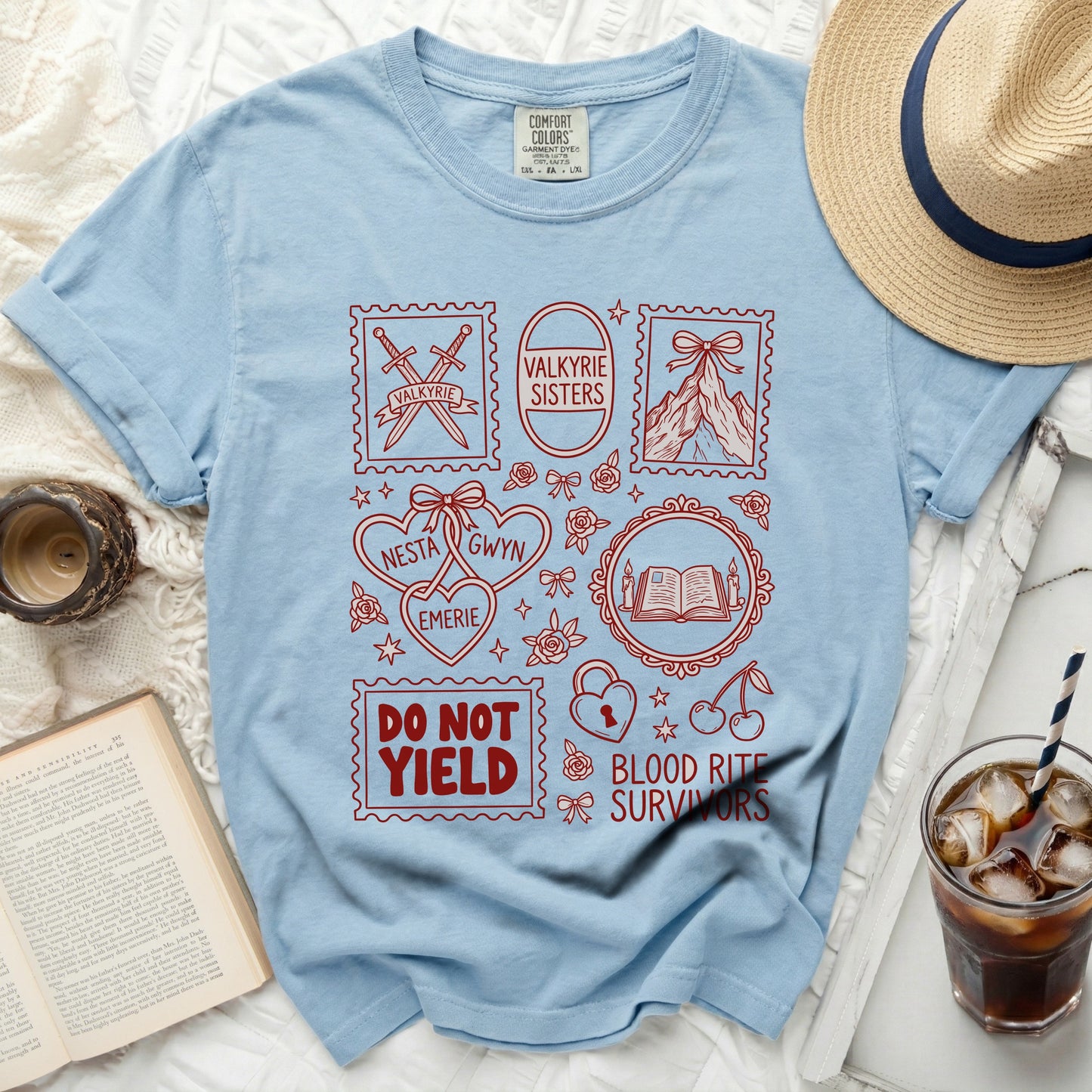 Light blue t-shirt with red stamps featuring swords, mountains, and text: Valkyrie, Valkyrie Sisters, Nesta, Emerie, Gwyn, Do Not Yield, Blood Rite Survivors.