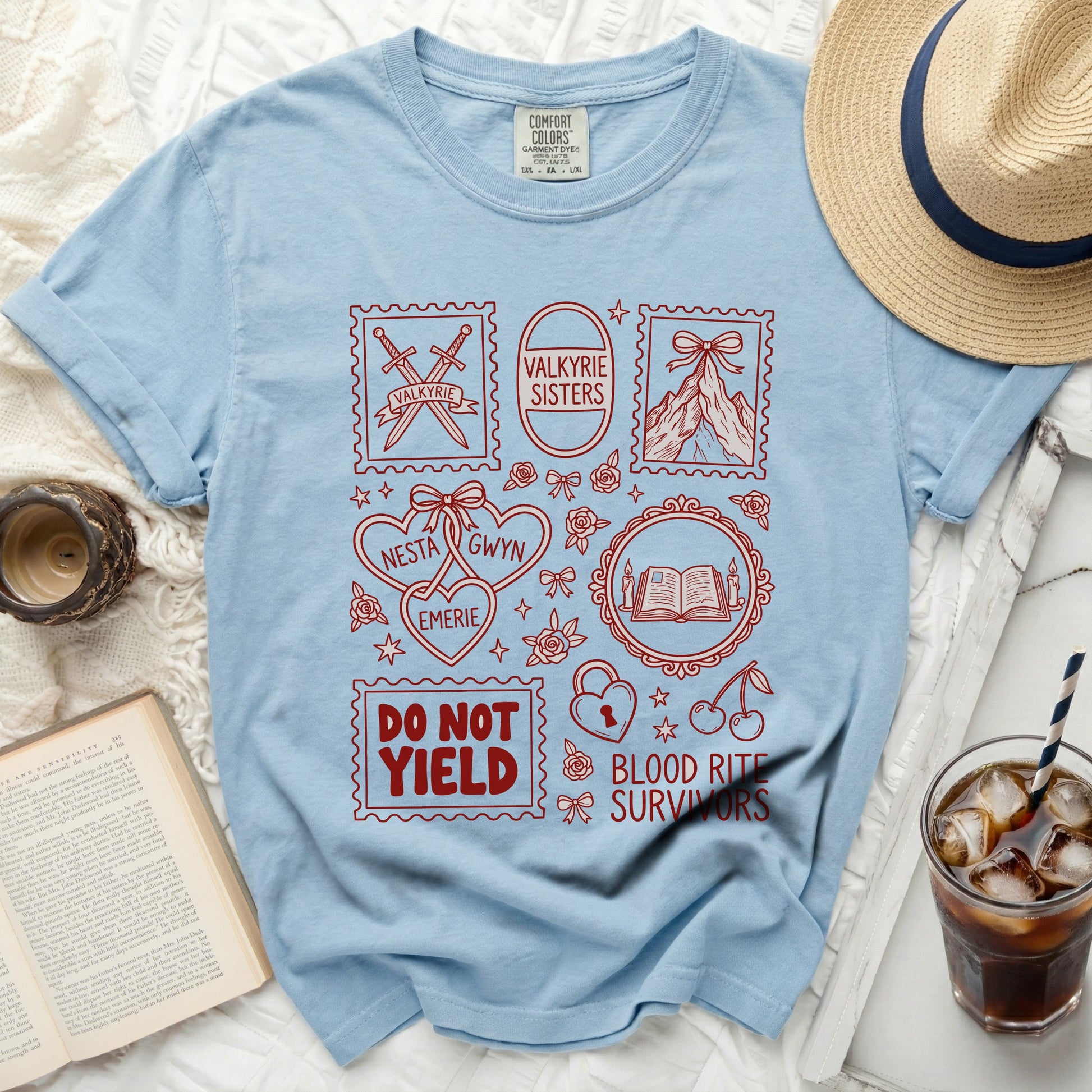 Light blue t-shirt with red stamps featuring swords, mountains, and text: Valkyrie, Valkyrie Sisters, Nesta, Emerie, Gwyn, Do Not Yield, Blood Rite Survivors.