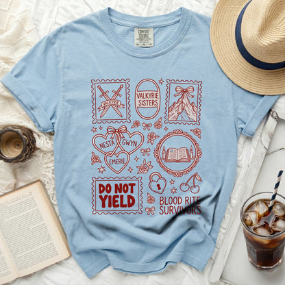 Light blue t-shirt with red stamps featuring swords, mountains, and text: Valkyrie, Valkyrie Sisters, Nesta, Emerie, Gwyn, Do Not Yield, Blood Rite Survivors.
