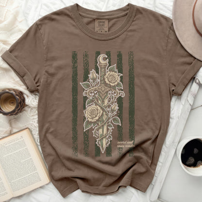 Brown t-shirt with a sword and roses design and "sword and roses reader" text.