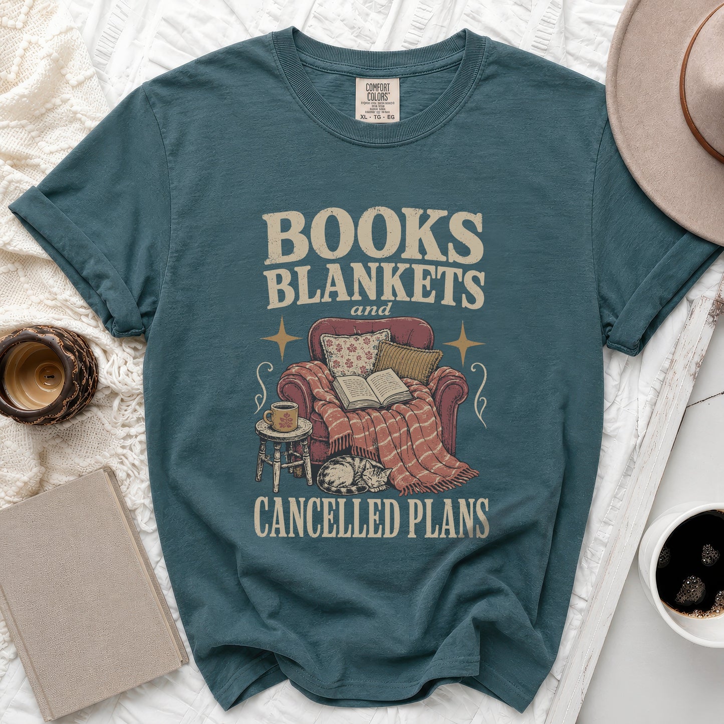 Teal t-shirt with "BOOKS BLANKETS and CANCELLED PLANS" graphic.