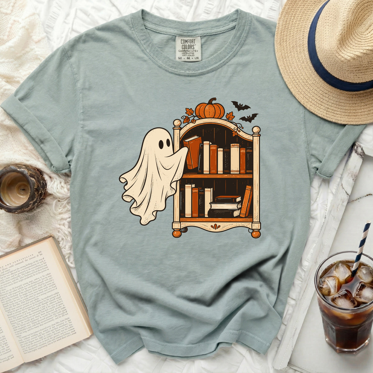 Ghost reaching for books on shelf with pumpkin and bats, Comfort Colors tag visible.