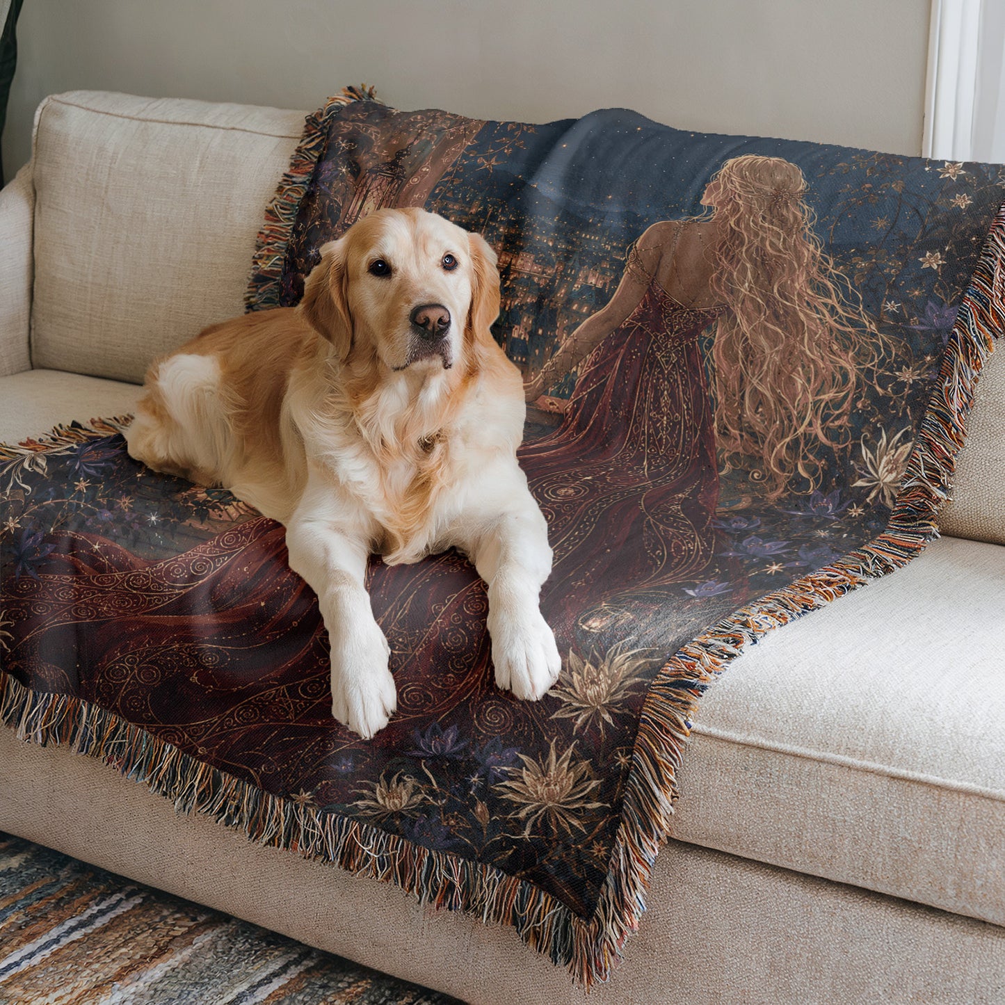 A golden retriever dog is lying on a couch, with a decorative blanket featuring a woman's image on it.