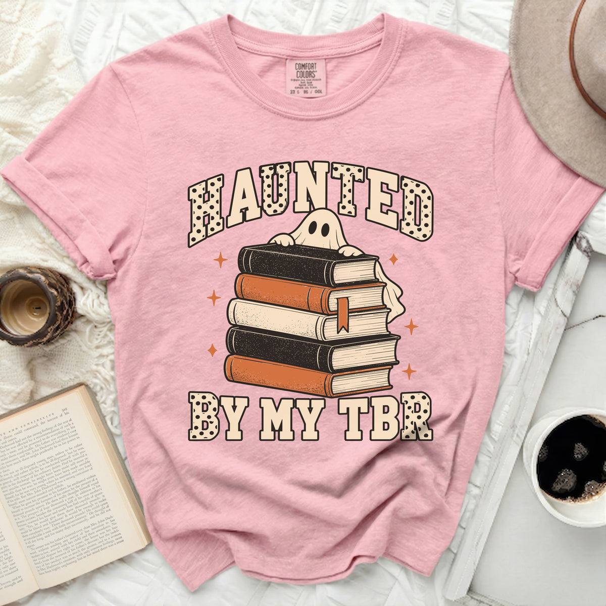 Pink t-shirt with "Haunted by My TBR" text and a ghost on books.
