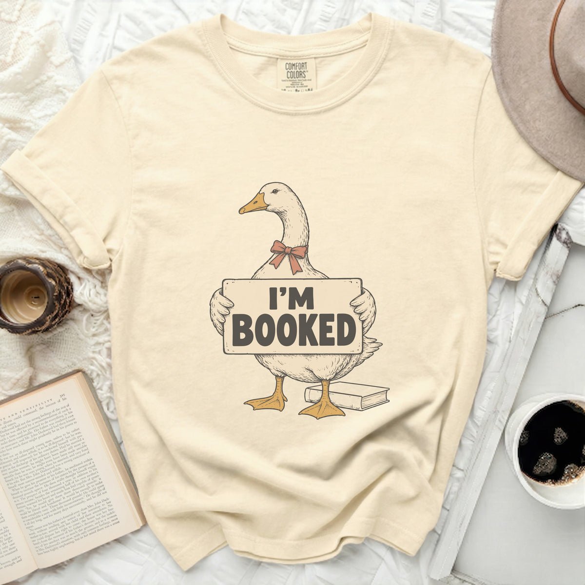 Goose wearing a red bow holding a sign that says "I'M BOOKED".
