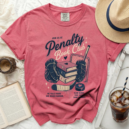Pink t-shirt with "Penalty Book Club" text and hockey imagery.