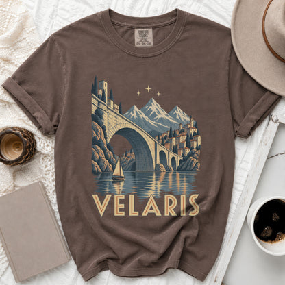 Brown t-shirt with graphic of Velaris cityscape, bridge, mountains, and sailboat.