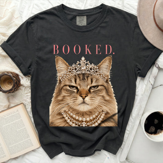 Black t-shirt with a cat wearing a crown and pearls, text "BOOKED."