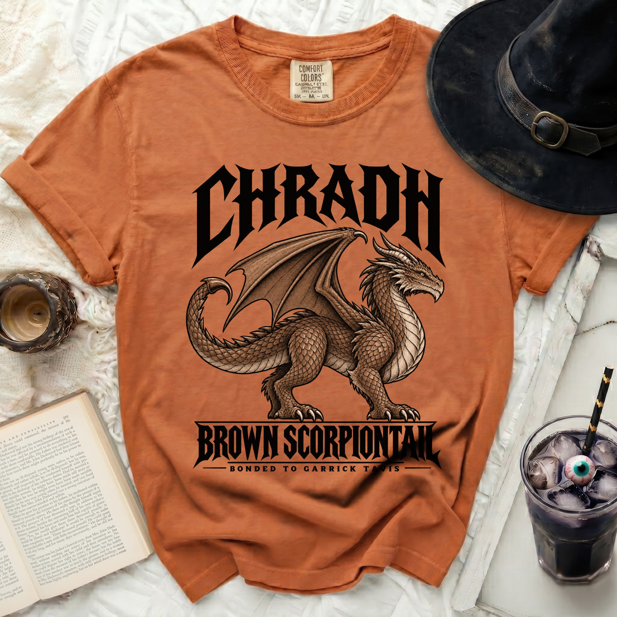Orange t-shirt with a brown dragon graphic and text: "CHRADH BROWN SCORPIONTAIL BONDED TO GARRICK TAVIS".