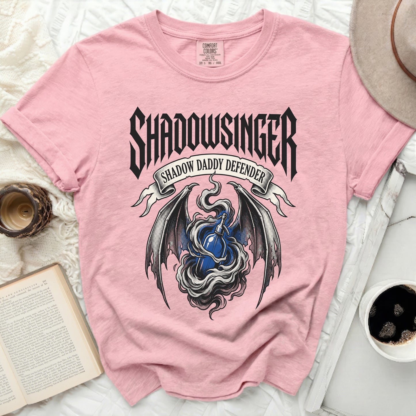 Pink t-shirt with "Shadowsinger Shadow Daddy Defender" graphic and blue soda bottle.