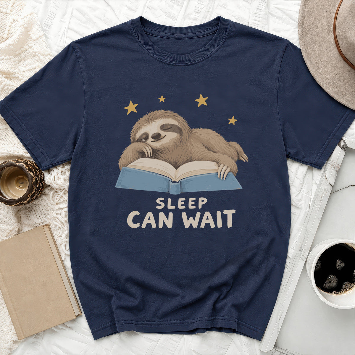 Dark blue t-shirt with a sleeping sloth on an open book and "SLEEP CAN WAIT" text.
