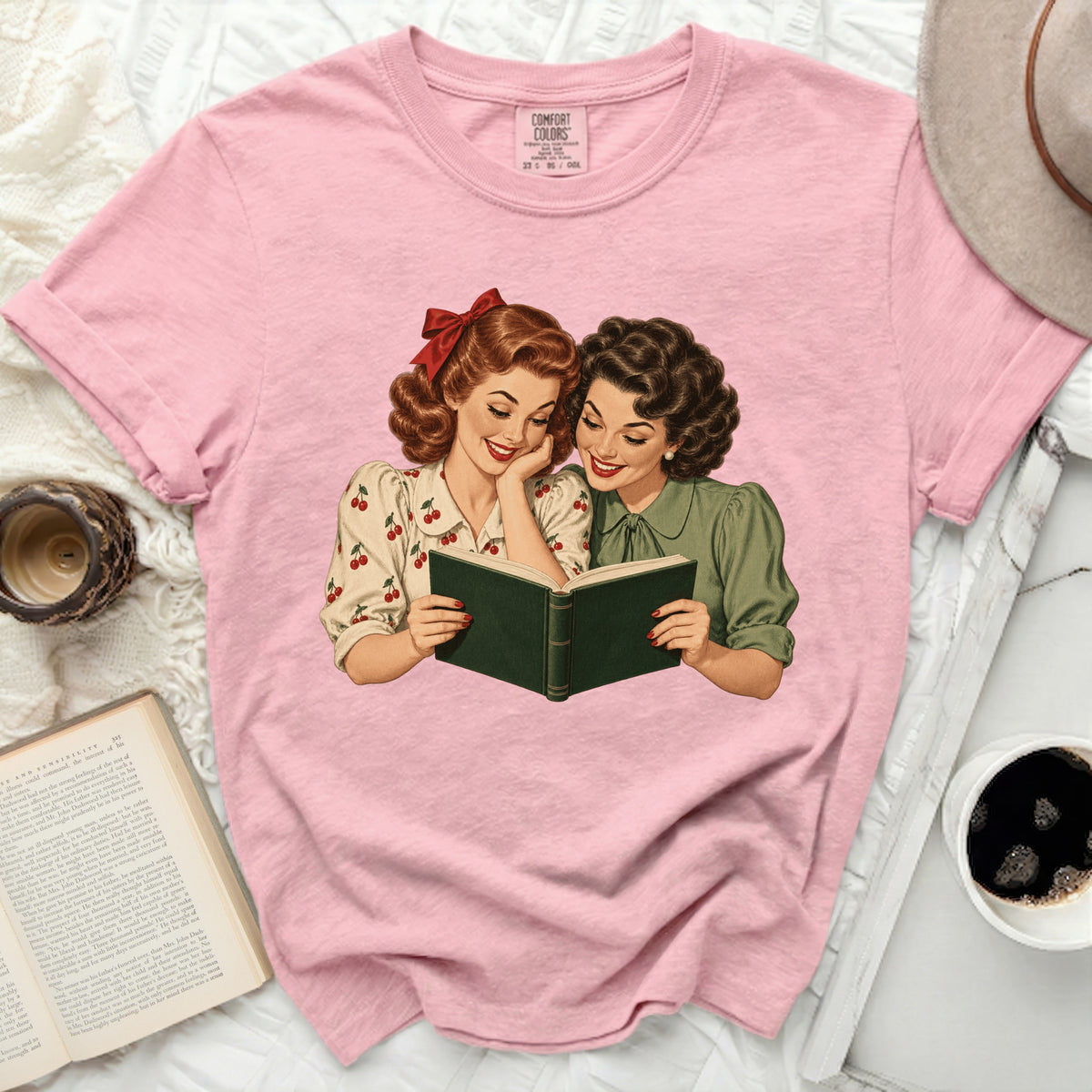 Pink t-shirt with retro illustration of two women reading a book.
