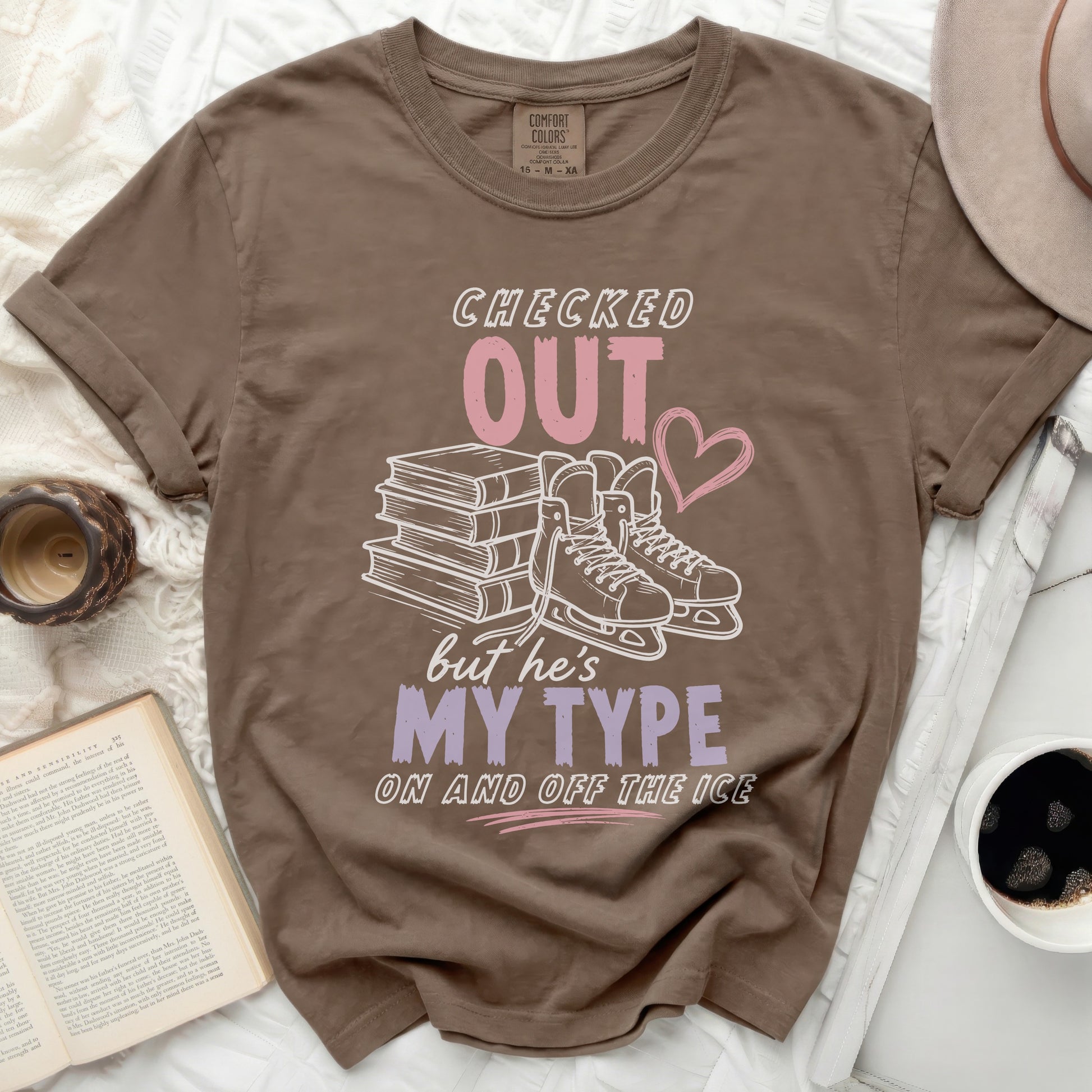 Brown t-shirt with "Checked Out But He's My Type" text and ice skates.