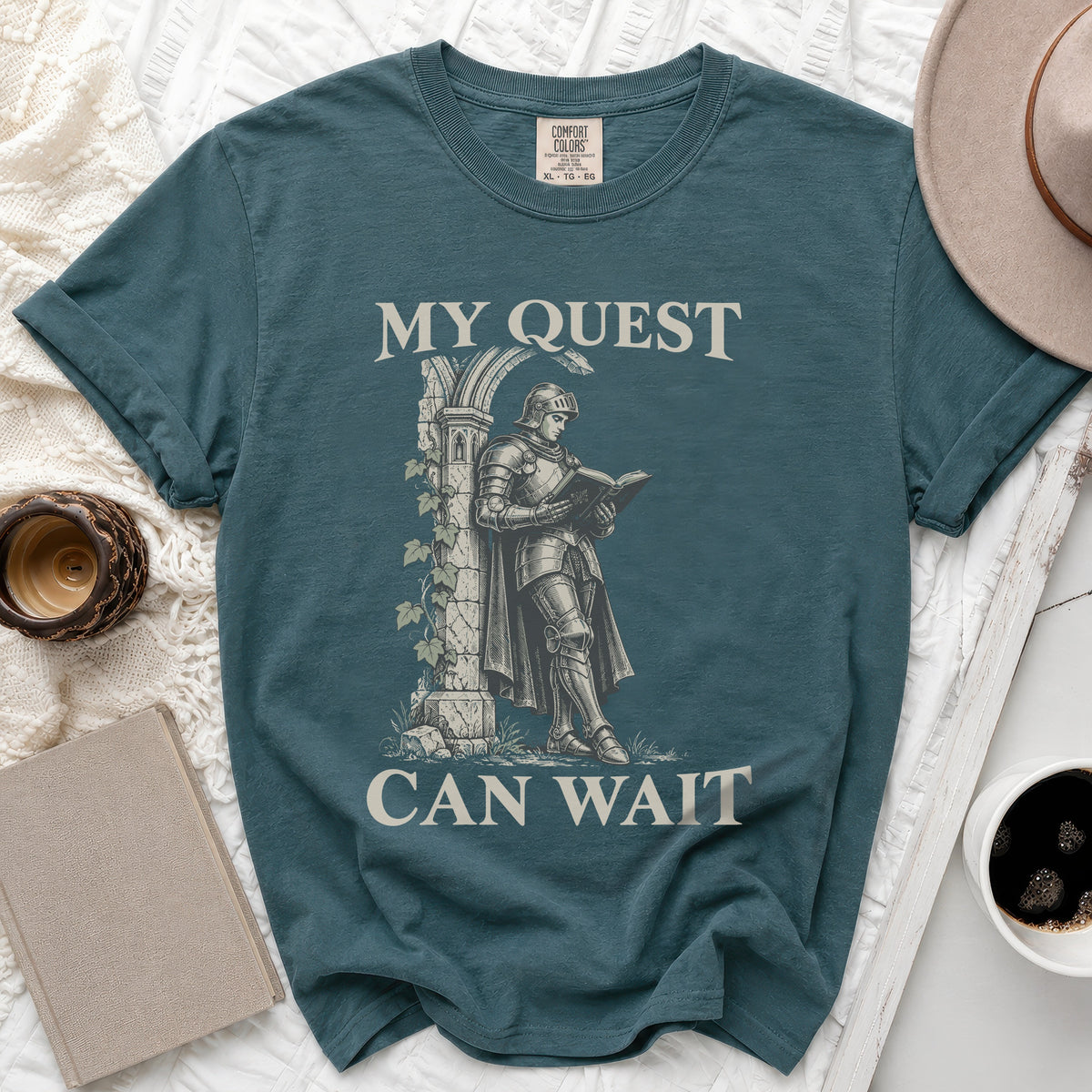 Teal t-shirt with knight reading under arch, text "MY QUEST CAN WAIT".