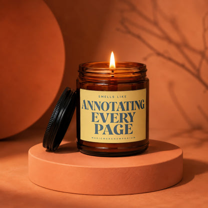 Amber glass candle with lit wick reading "Smells Like Annotating Every Page".