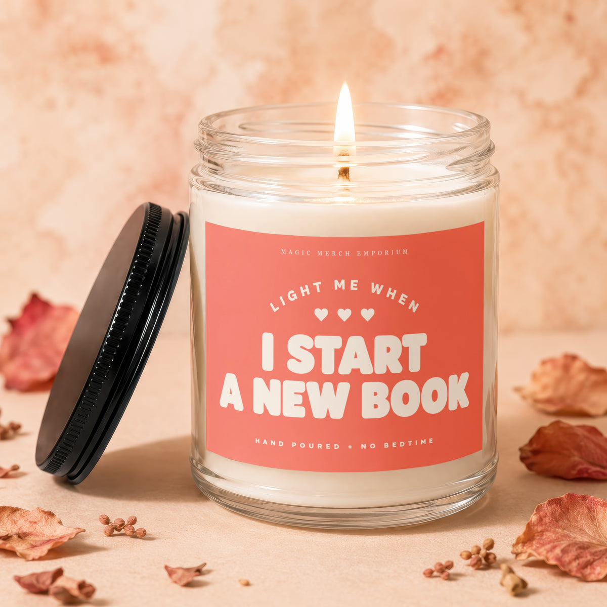 Glass candle with burning wick, reading "Light me when I start a new book".