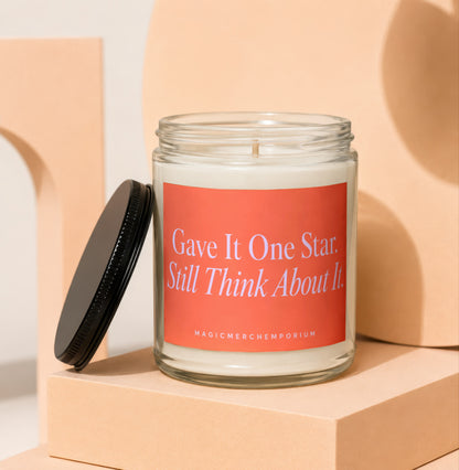 Candle in glass jar with coral label reading "Gave It One Star. Still Think About It."