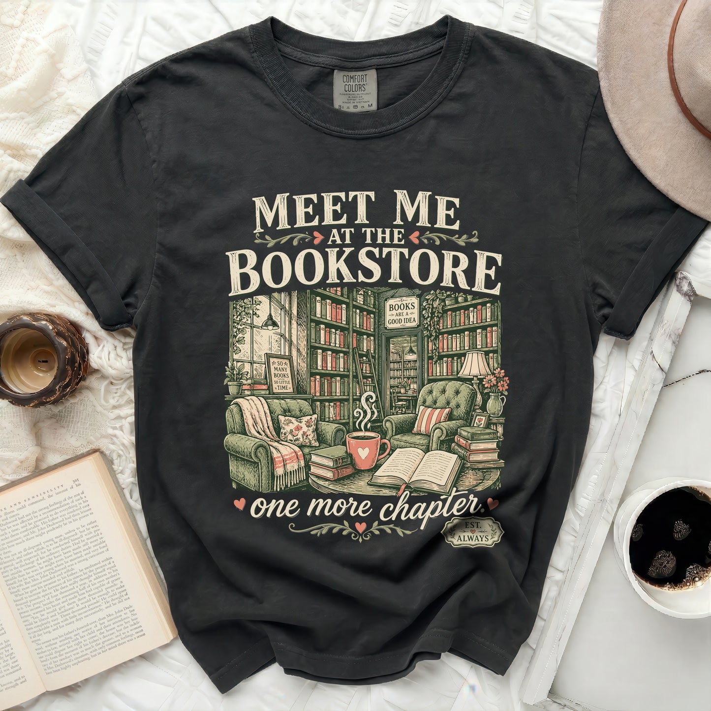 Black t-shirt with "Meet Me at the Bookstore" and books, chairs, and coffee illustration.