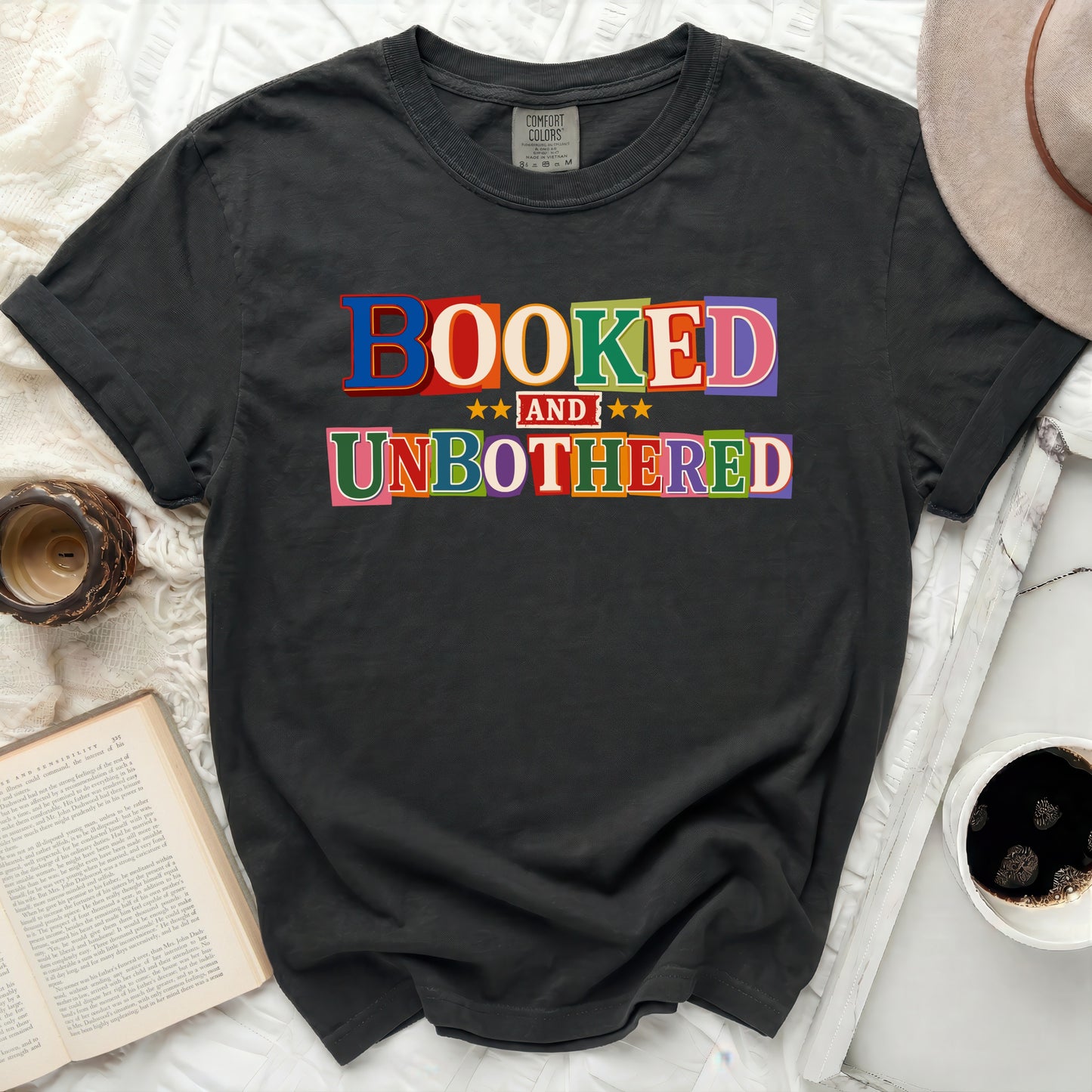 Black t-shirt with "BOOKED AND UNBOTHERED" text in colorful letters.