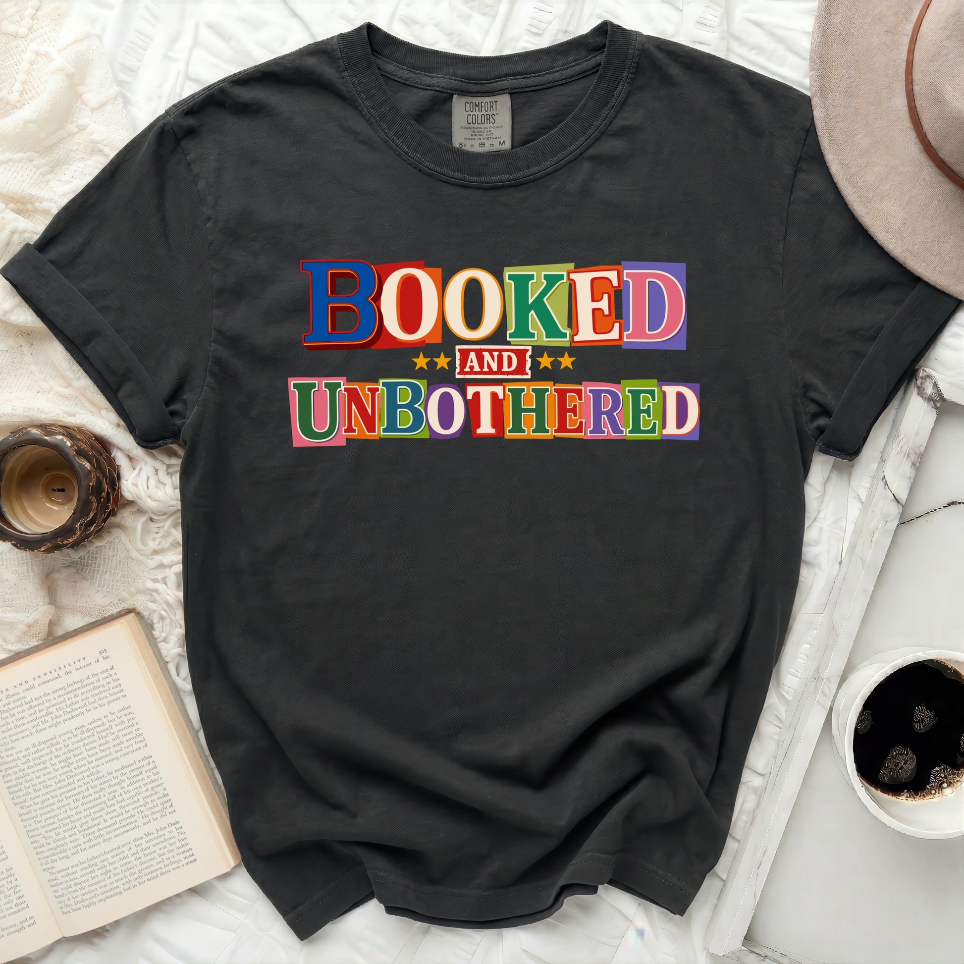 Black t-shirt with "BOOKED AND UNBOTHERED" text in colorful letters.